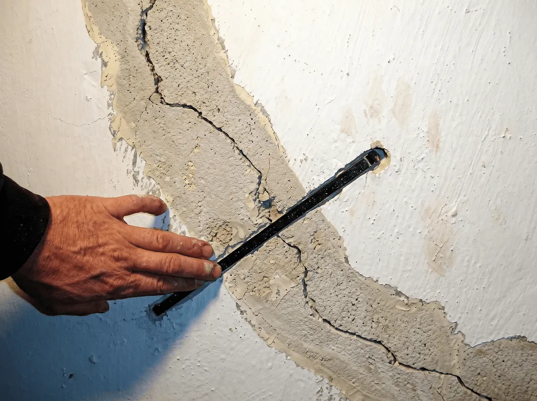 A wall with a large crack is being inspected by a professional in Boulder, CO